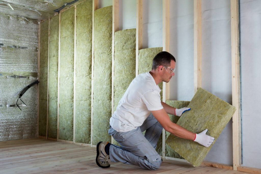 An insulation contractor works to add insulation to the interior wall of a home for more energy efficiency