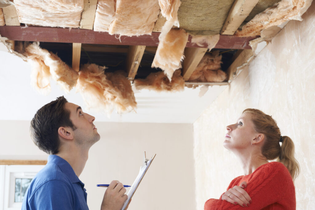 A home inspector evaluates faulty insulation while the homeowner watches