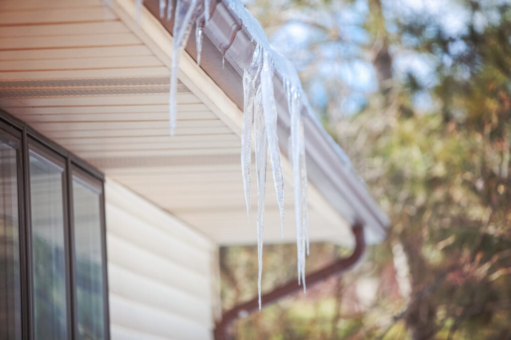 Icicles formed on the edge of a home’s gutter, indicating an ice dam on the roof.