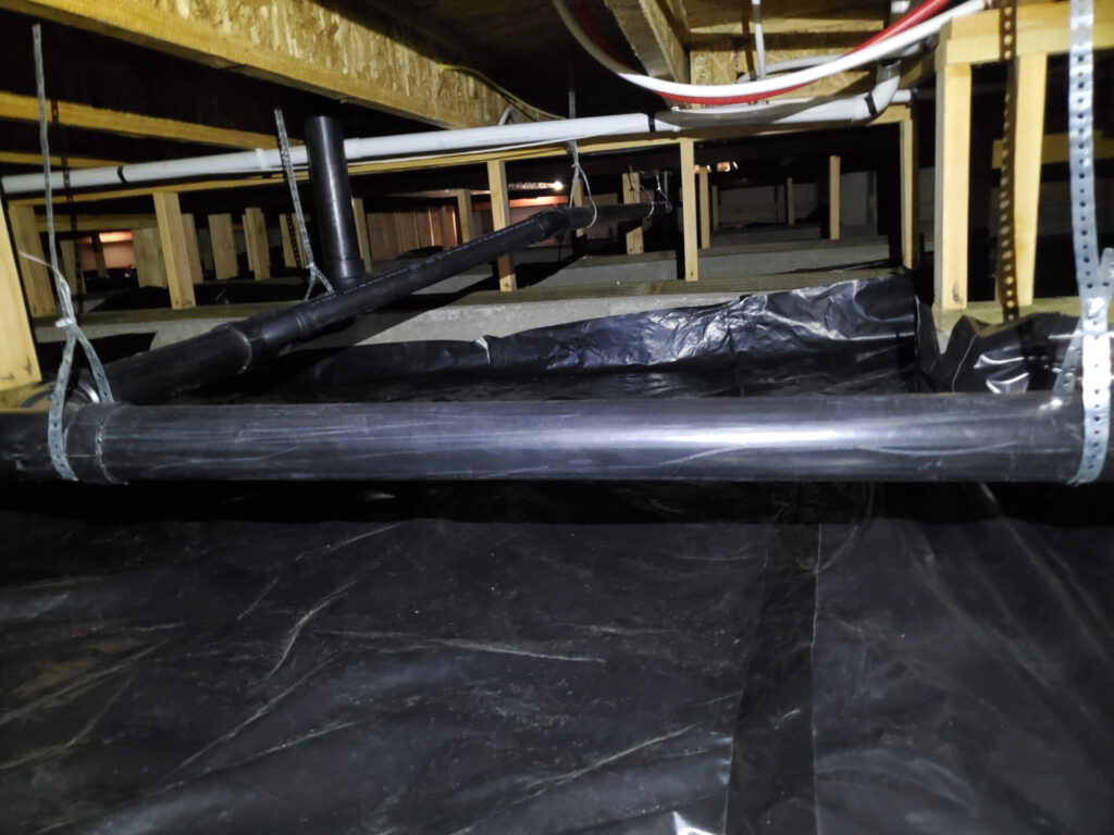 A crawl space under a home with an installed vapor barrier.  