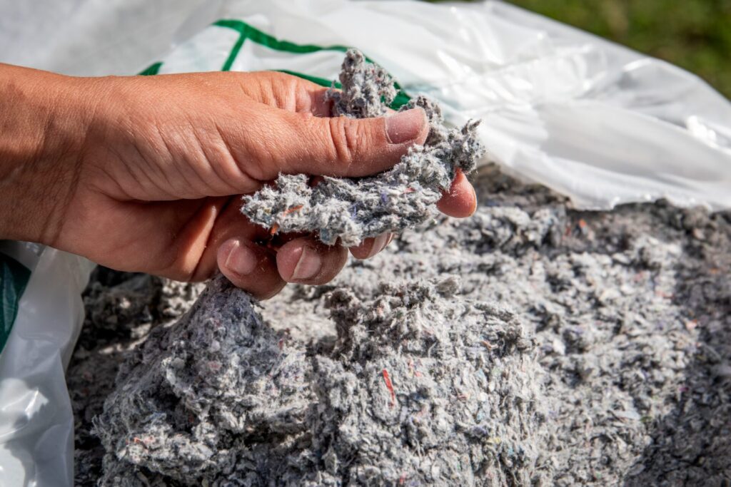 A hand holds cellulose insulation, made from recycled materials