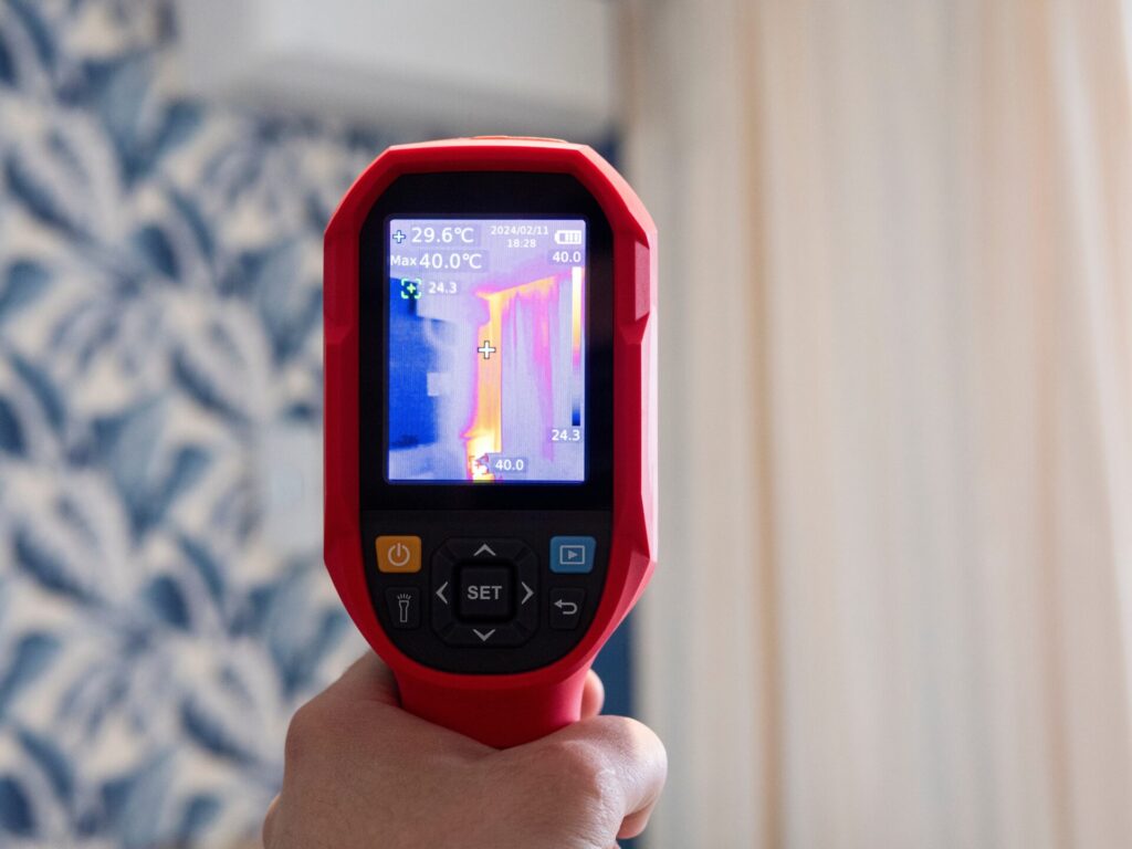 A thermal camera is pointed at an interior wall looking for hot or cold points