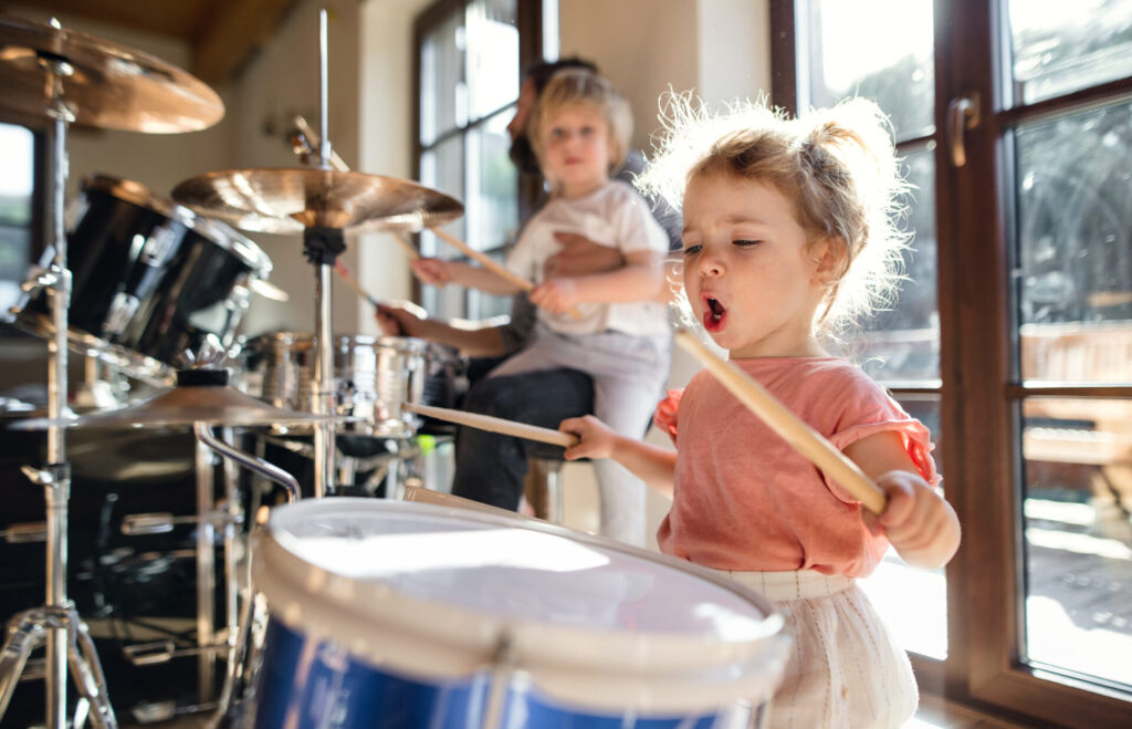 Small girl indoors at home, playing drums.