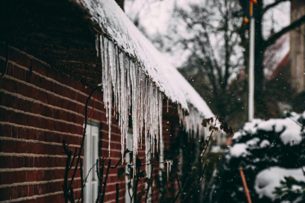 Icicles hang from the roof of a brick house in winter